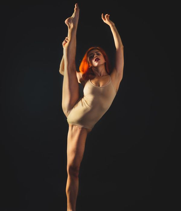 Athletic woman performing energetic movements in a warm amber lit studio.
